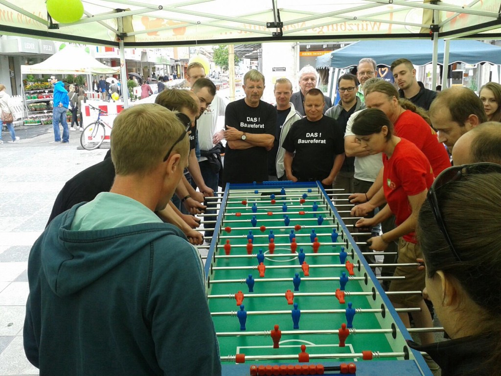 Eine Gruppe von Menschen steht um einen Tischfußballtisch, während sie intensives Spiel und Wettbewerbsgeist zeigen.