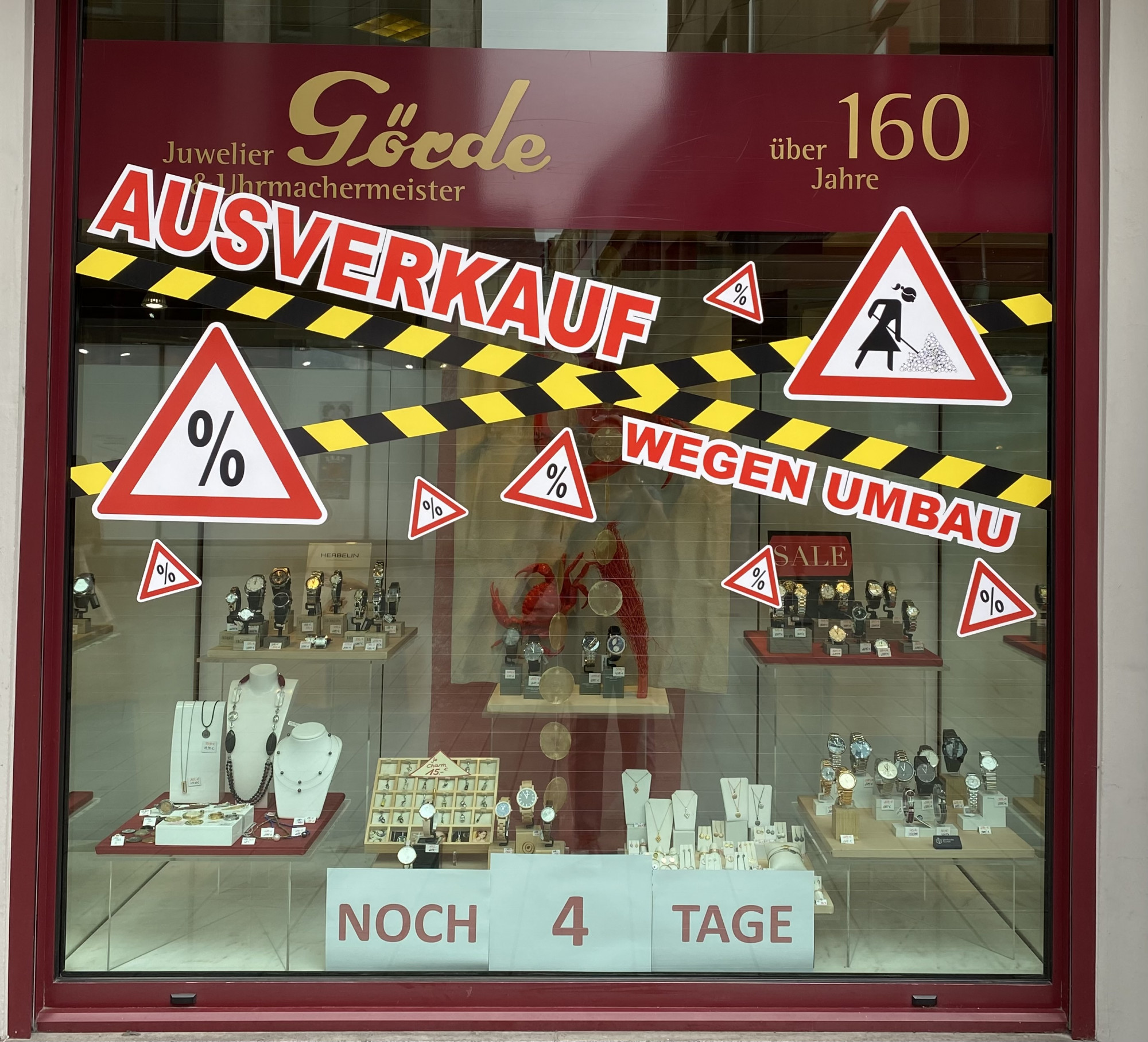 Das Schaufenster zeigt Schmuckstücke und Uhren, mit einem auffälligen Hinweis auf einen Ausverkauf wegen Umbauarbeiten. Sichtbare Rabattschilder und eine Countdown-Anzeige mit 